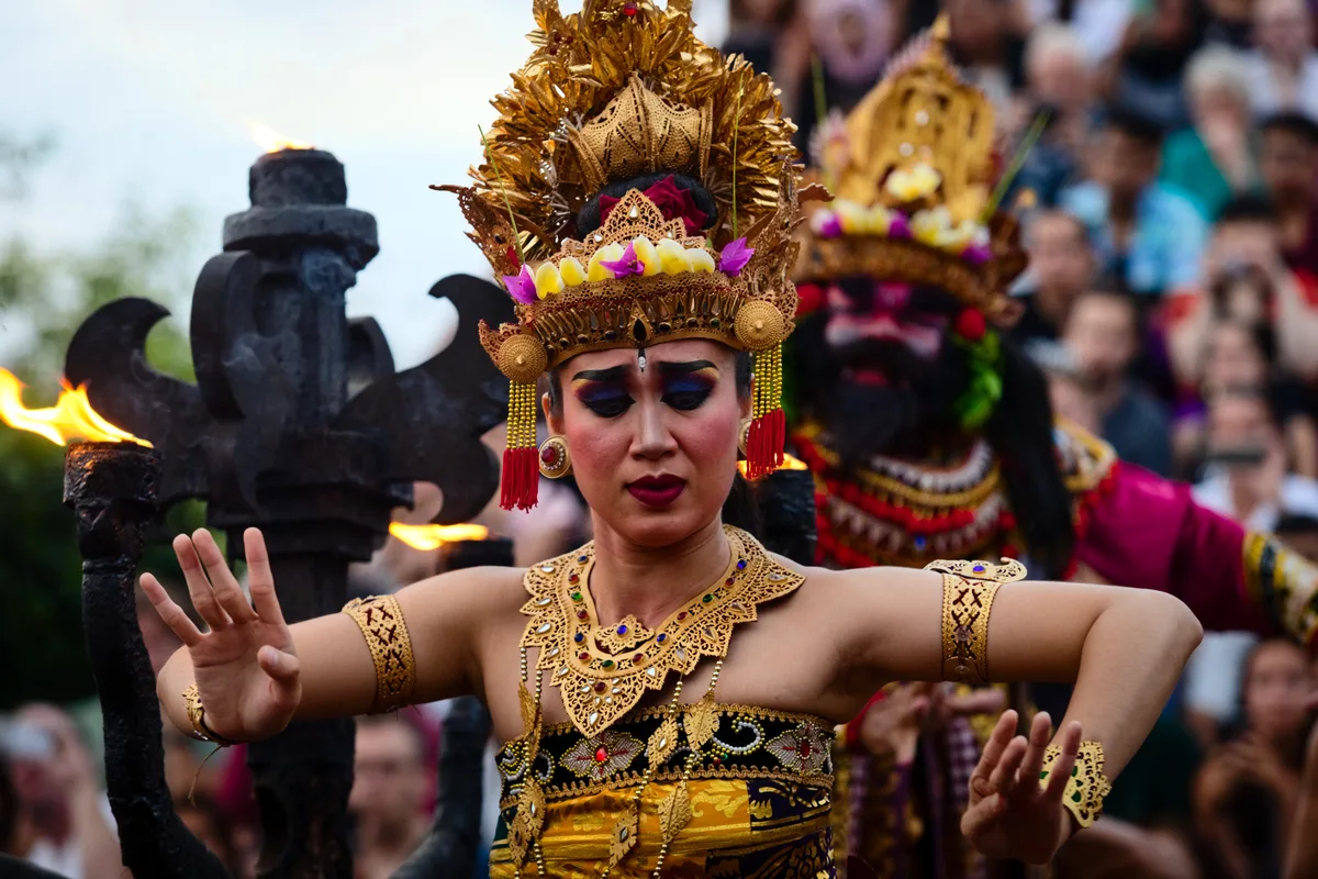 A costumed dancer in gold headdress performing during the Kecak show at Uluwatu